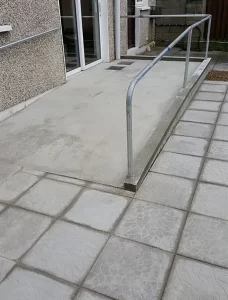 Paving and wheelchair accessible ramp, with railing.